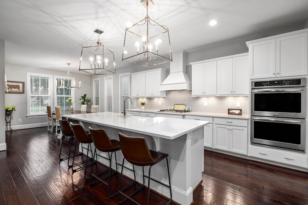 Sleek modern kitchen featuring white cabinetry, spacious island, and stylish lighting for a contemporary home design.