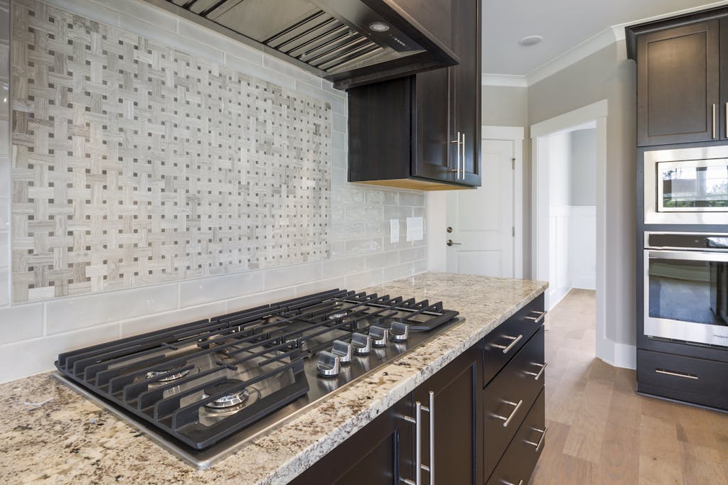 Contemporary kitchen featuring a sleek granite countertop, integrated oven, and stylish backsplash. Granite countertops Texas